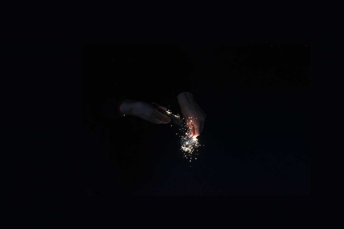 dark Hands ignite golden sparks using a flint in the dark fire