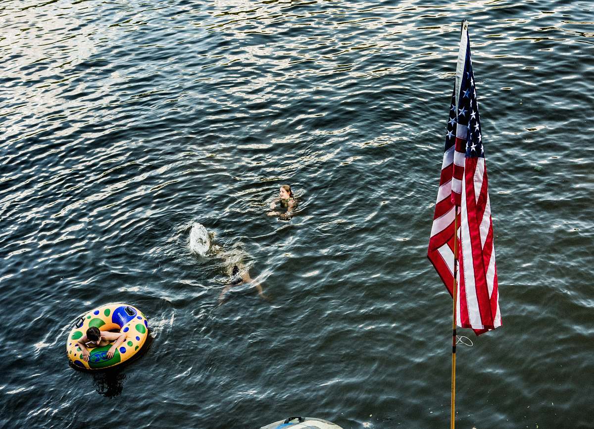water three person swimming in body of water near US flag swim