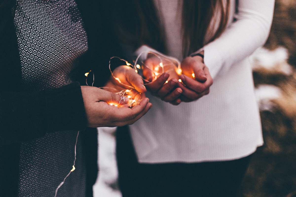 person close-up photo of two person holding lighted string lights sea life