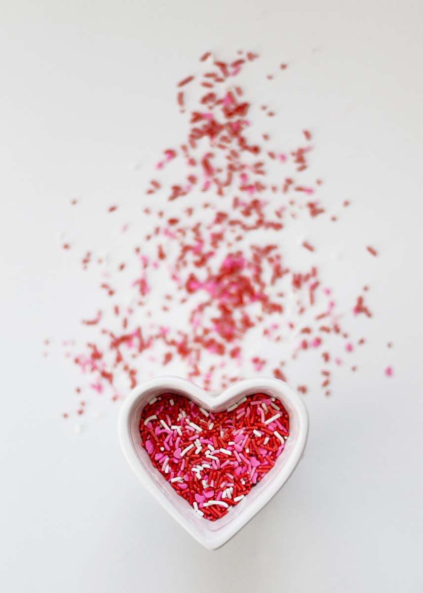 valentine selective focus photo ofsprinkles in heart ceramic bowl candy