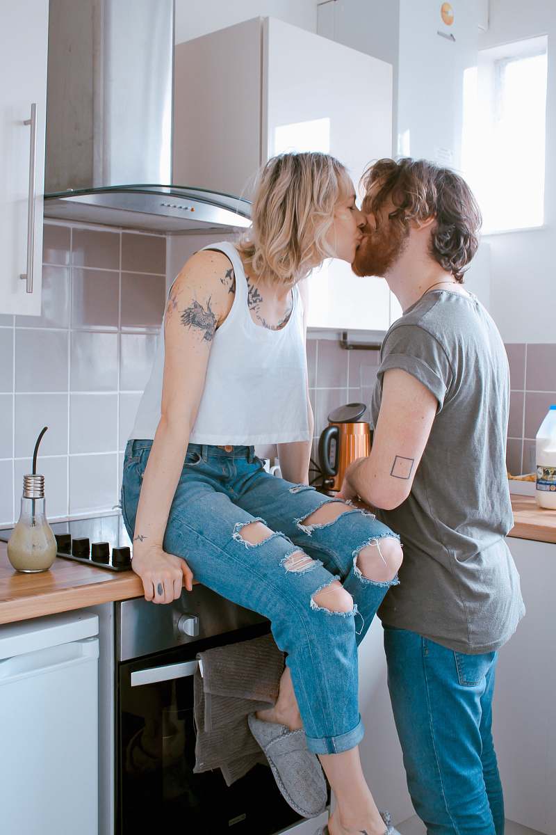 human man and woman kissing inside kitchen couple