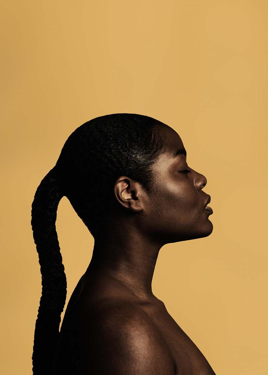 human braided woman taking photo beside yellow painted wall woman