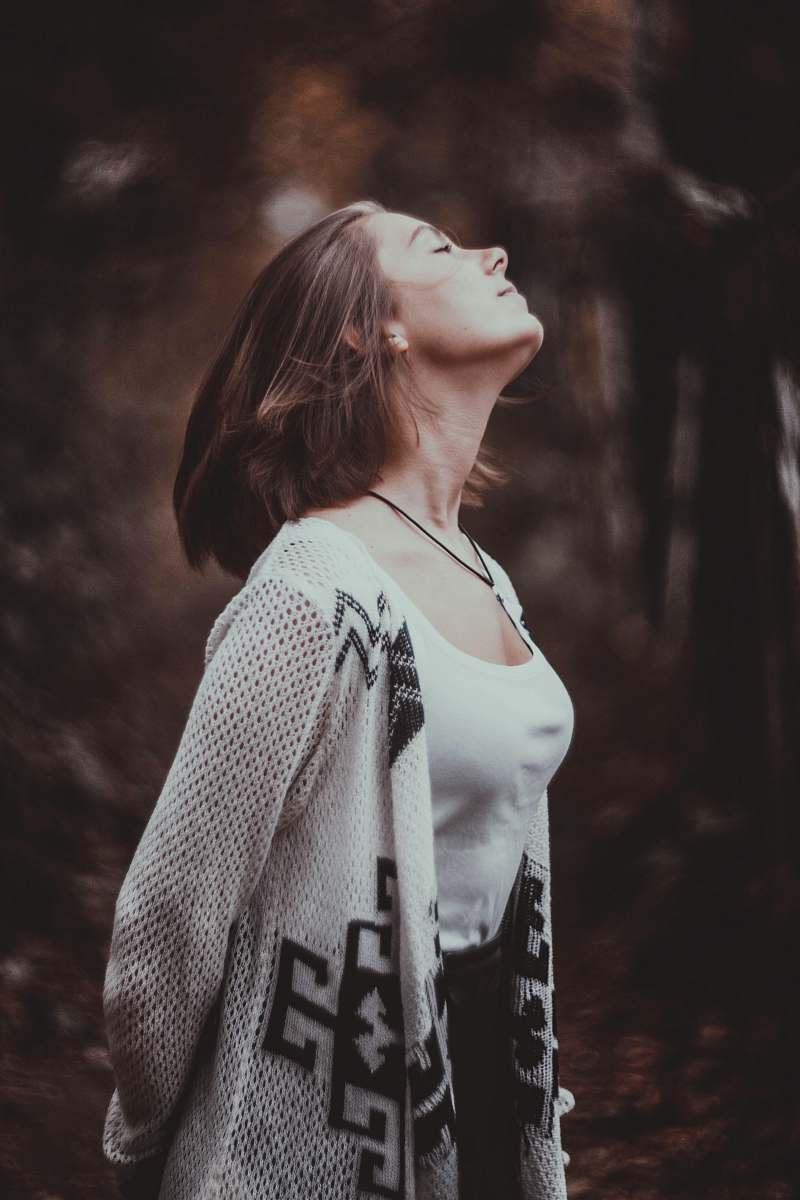 human standing woman in white scoop-neck tank top with beige cardigan with her eyes close in selective focus photography person