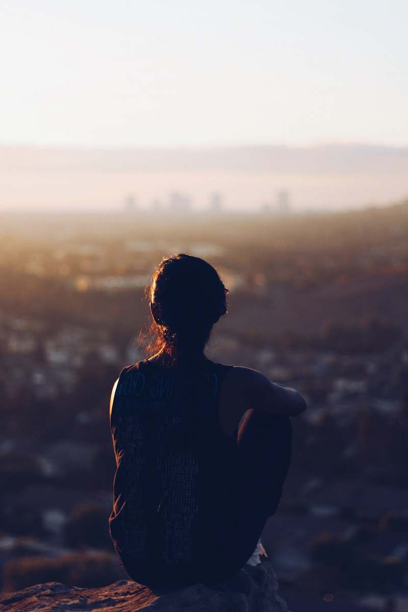 person woman sitting on brown rock during daytime woman