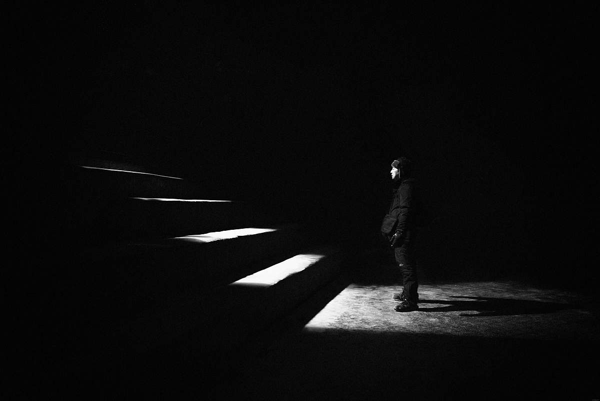 black grayscale photo of man standing in front of stairs white