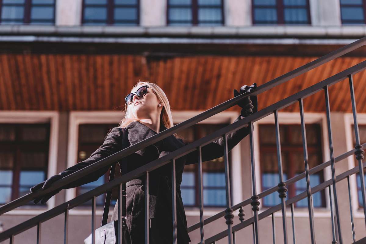 person woman standing on stair while holding rails during daytime railing