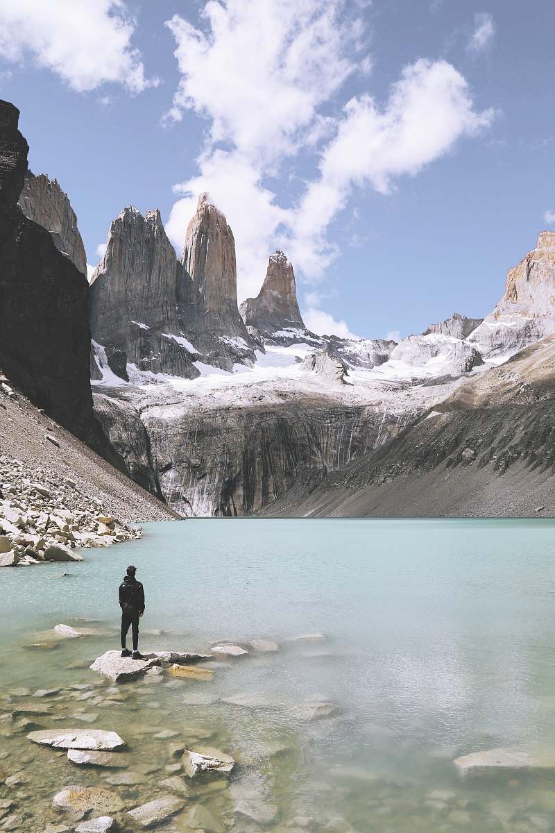 outdoors man standing above rock beside body of water under cloudy skies snow