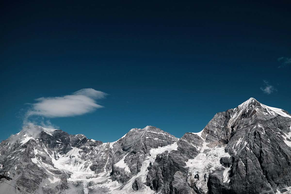 nature snow covered rocky mountain under clear sky at daytime outdoors