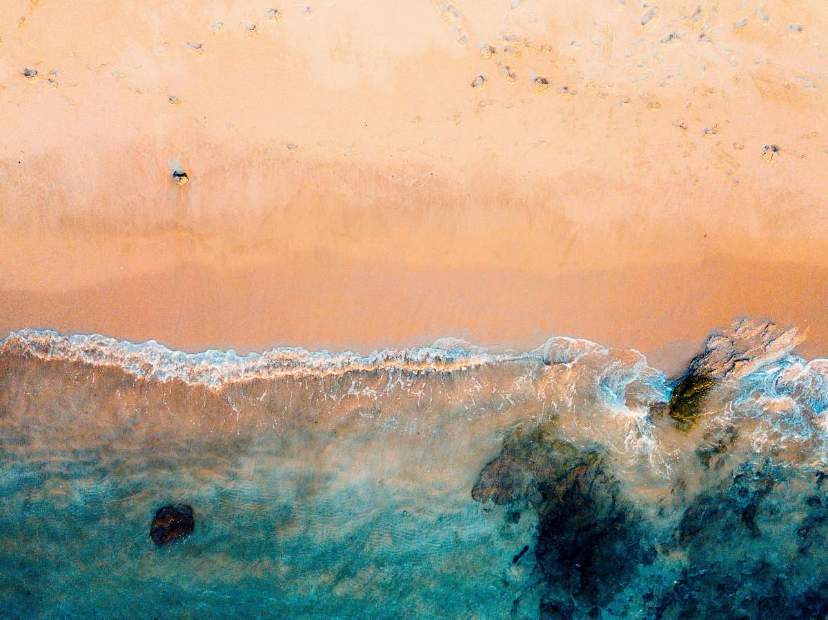 beach drone shot of beach and body of water on brown sand lampuuk beach