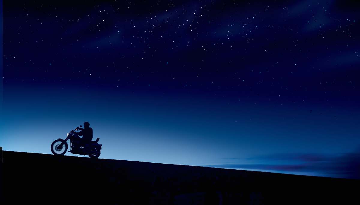 motorcycle person riding motorcycle under blue and black skies during night time vehicle