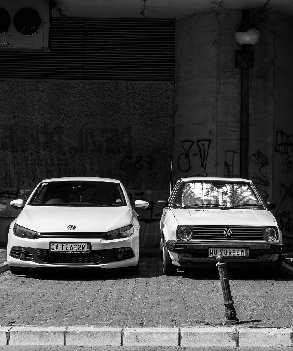 car grayscale photo of two Volkswagen cars parked on sidewalk automobile