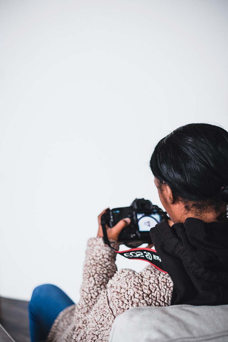 person man sitting on sofa using DSLR camera camera