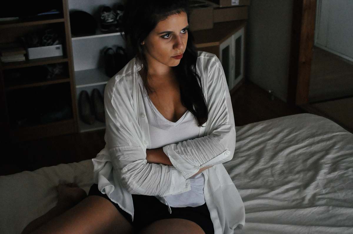apparel woman wearing white cardigan sitting on bed furniture