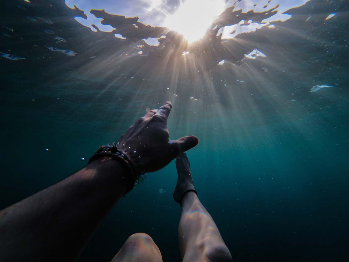light underwater photography of person soaking under sun rays grey