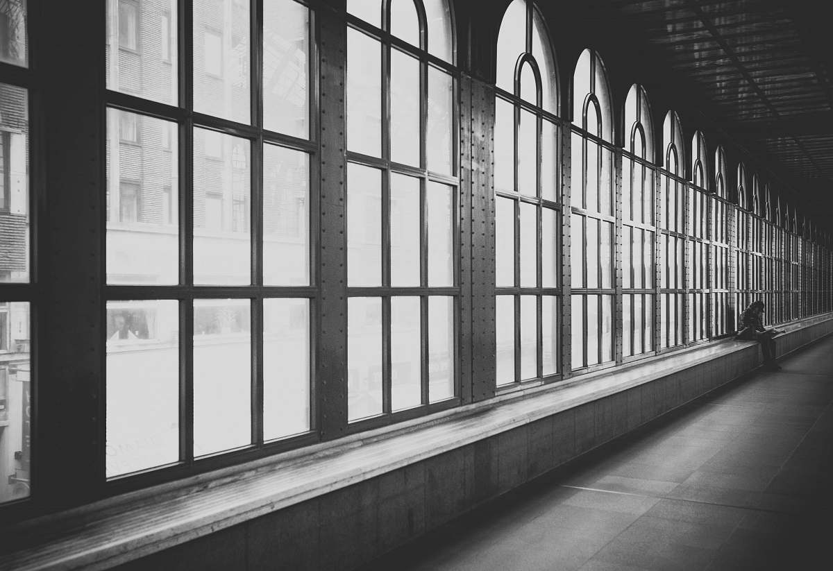 black-and-white person sitting on hallway architecture