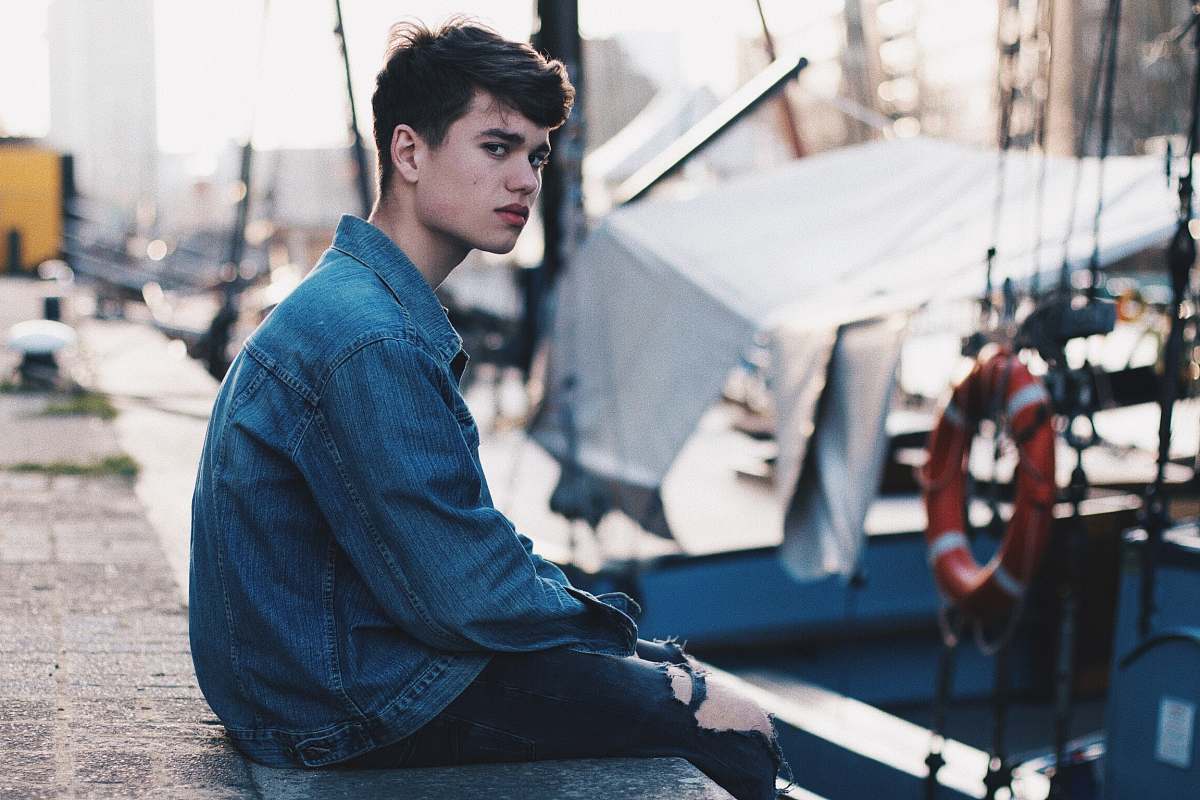 person man in blue denim jacket sitting on dock human