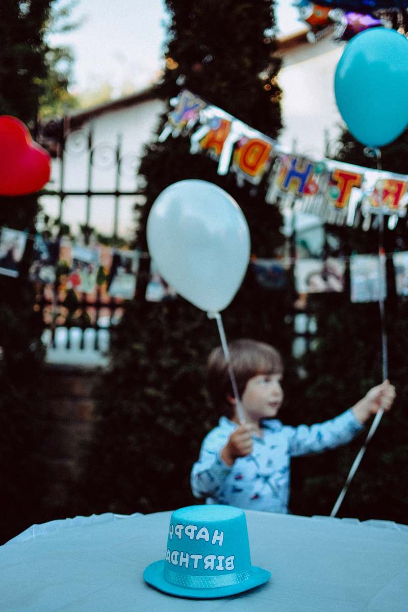 human boy holding blue and white balloons at the party people