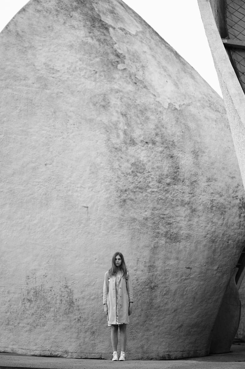 black-and-white grayscale photo of woman standing near building grey