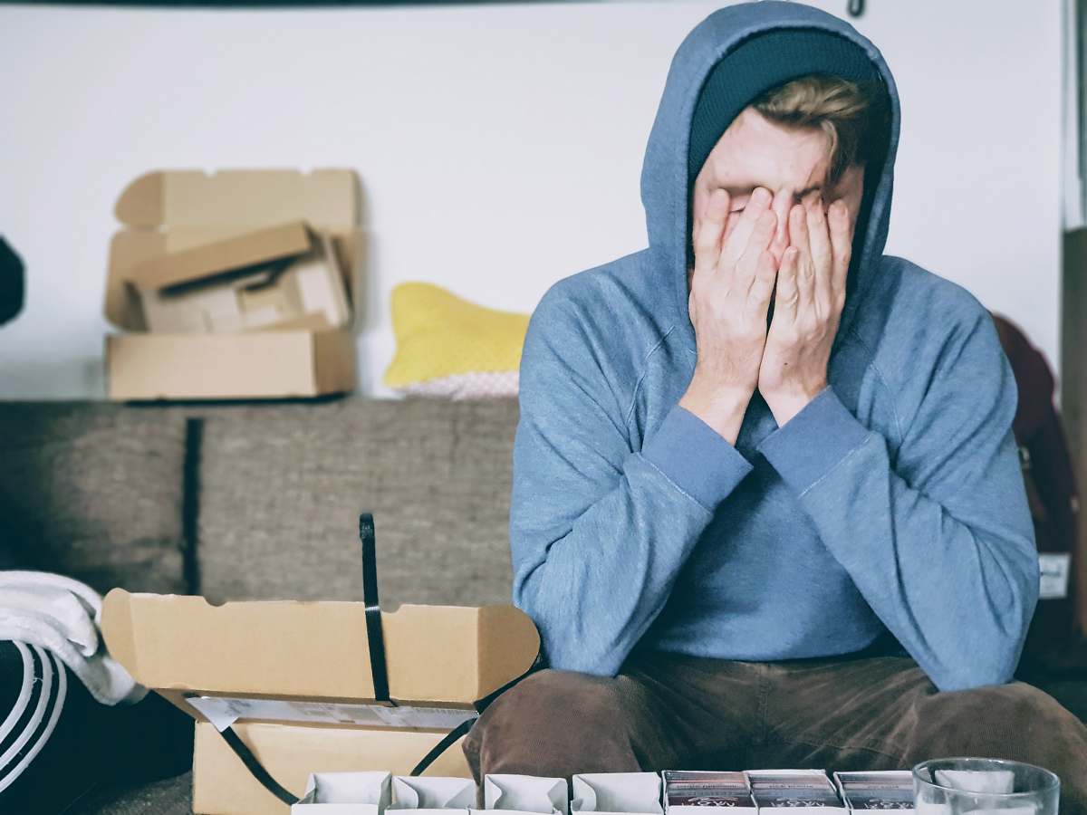 human man covering face with both hands while sitting on bench sitting