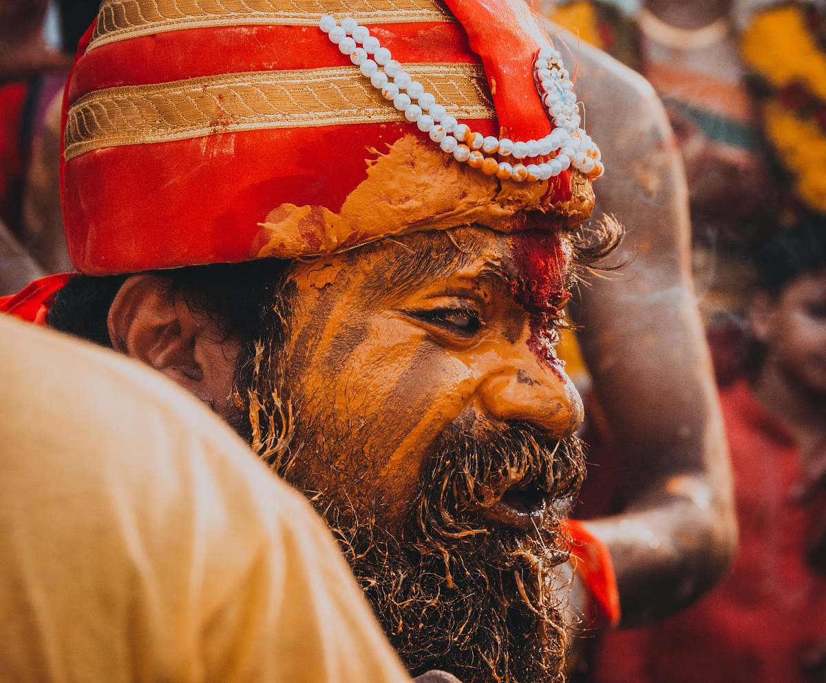 human man in gold and red striped head dress with painted face people