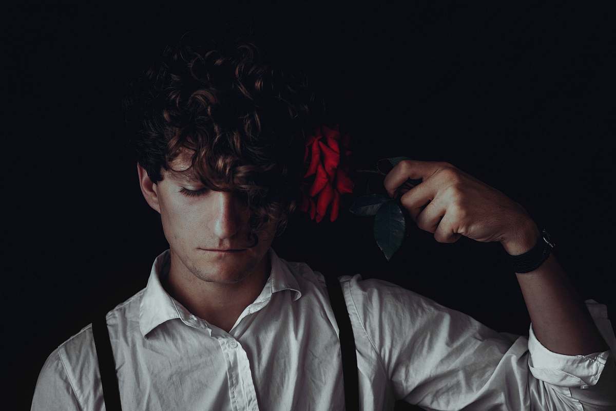 human man in white dress shirt holds red flower hair