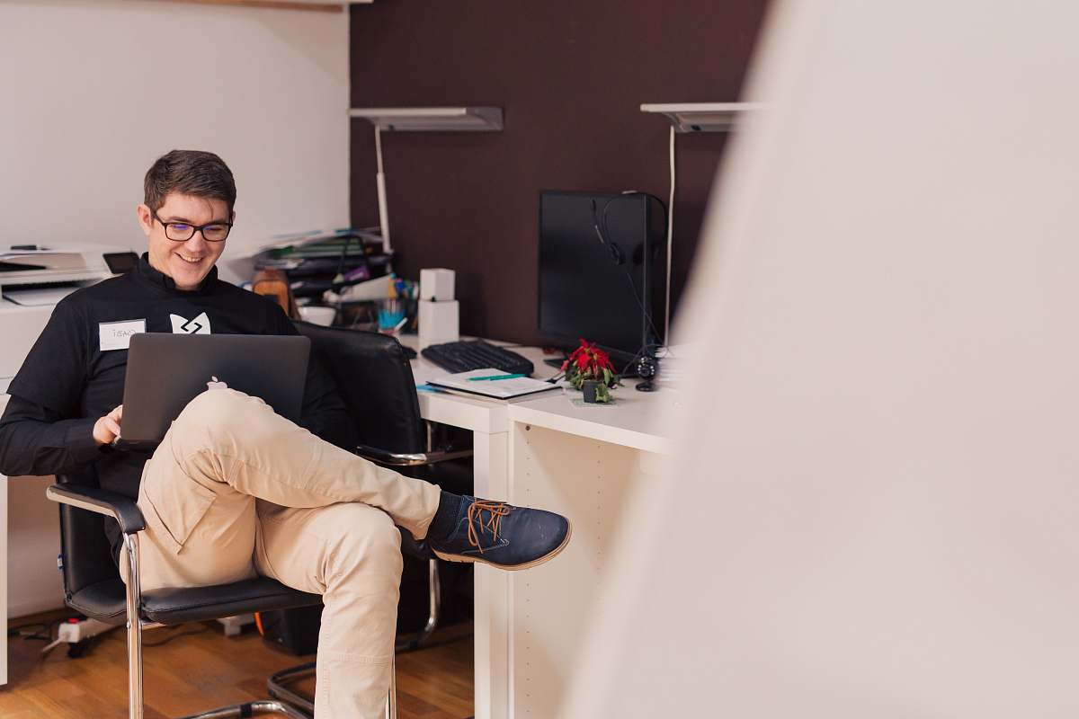 human man smiling while sitting and using MacBook people