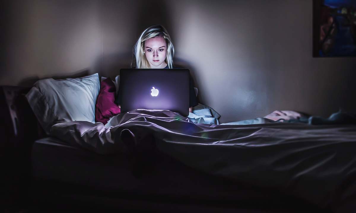 bed woman sitting on bed with MacBook on lap woman