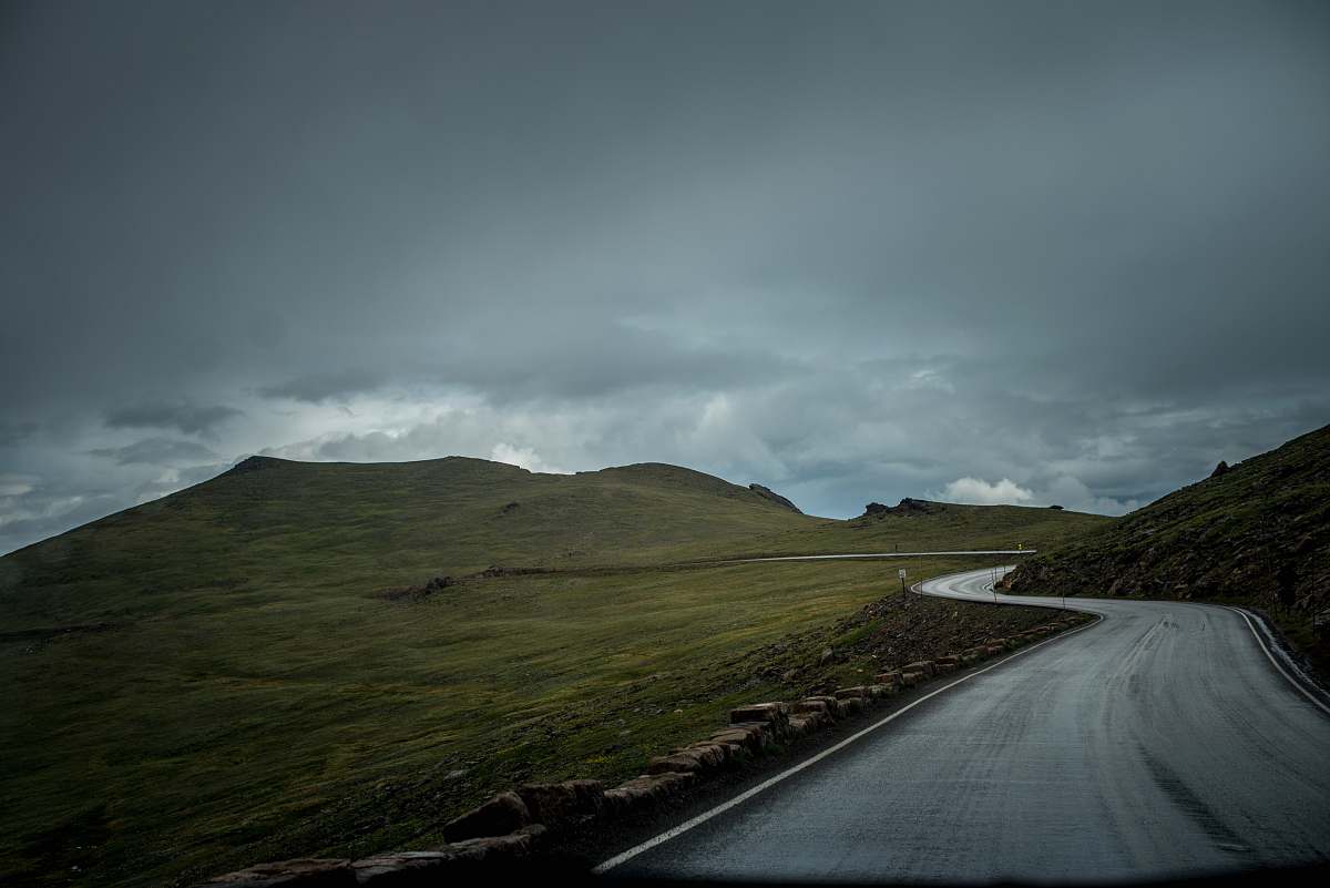 mountains photo of gray concrete road between green mountain and green grass field under cloudy sky empty