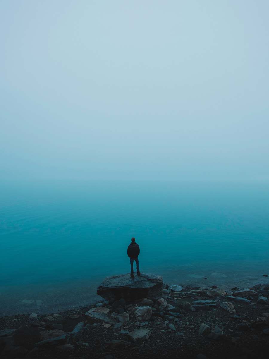 blue man standing on rock near body of water standing