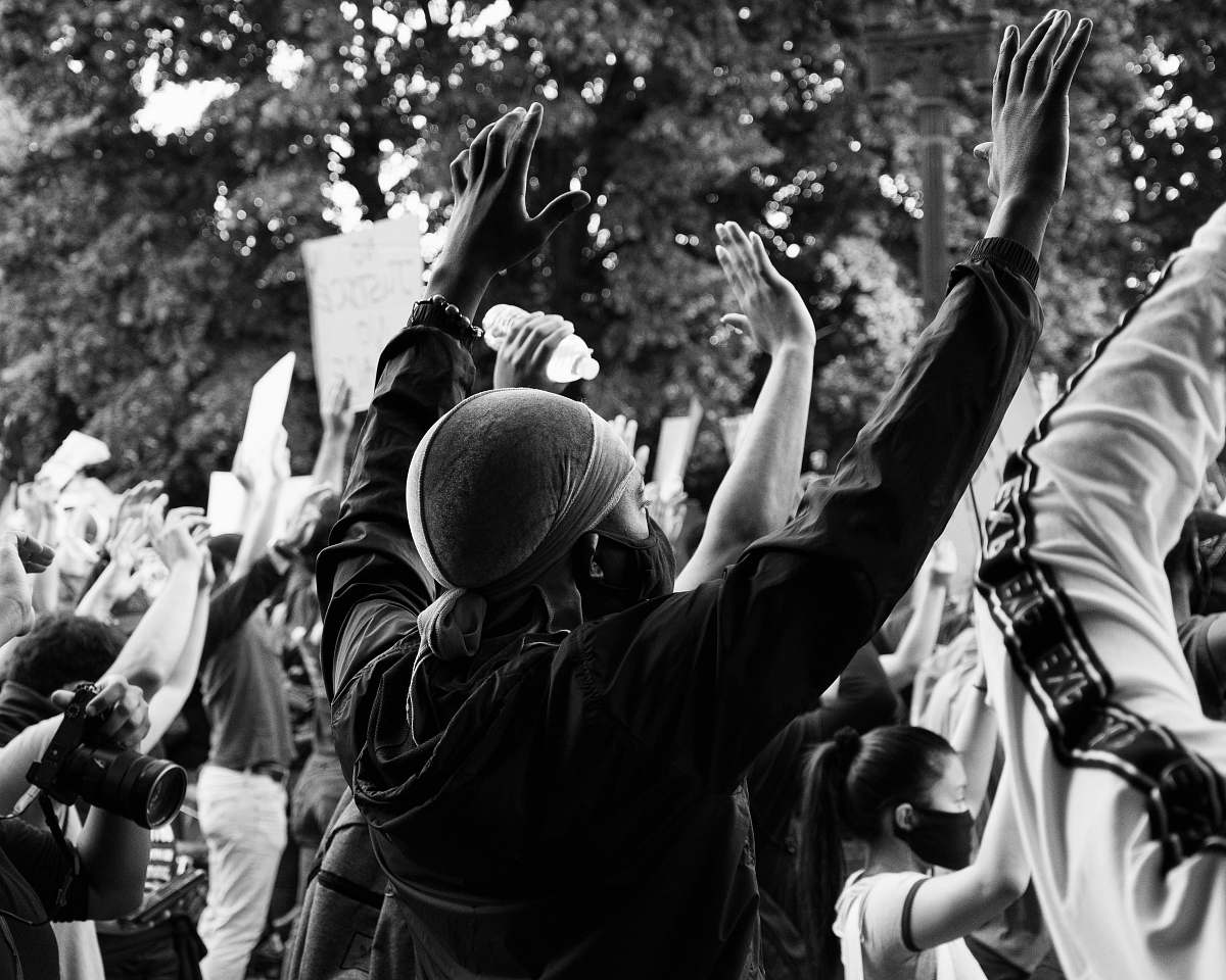 protest man in black jacket and man in black jacket holding man wearing hat crowd