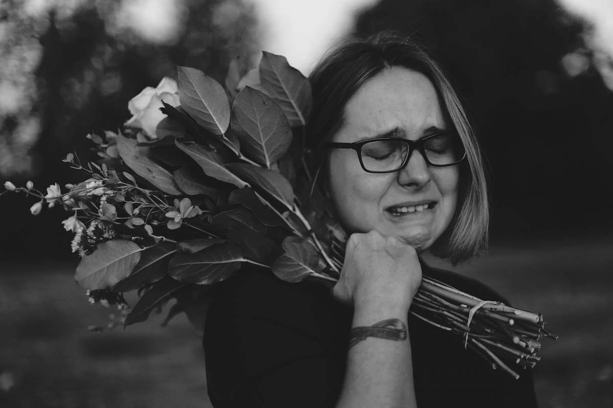person grayscale photo of crying woman holding bouquet of flowers human
