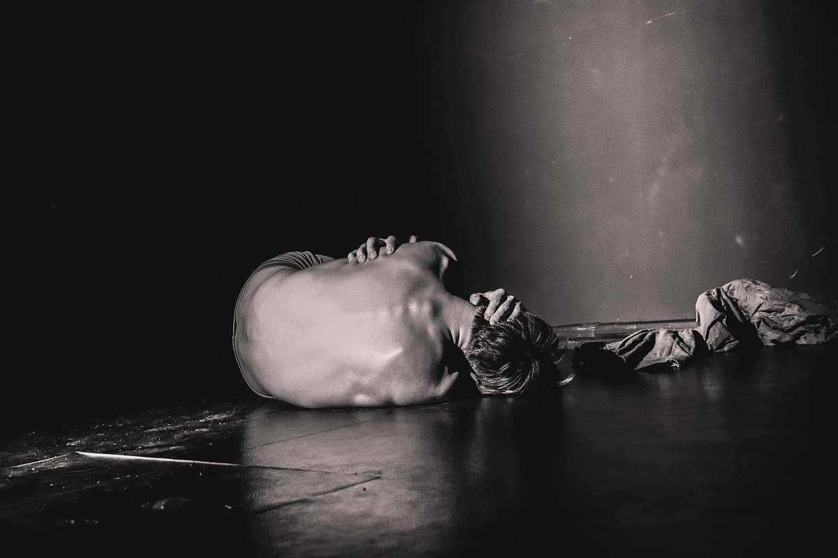 pain grayscale photography of man lying on floor sadness