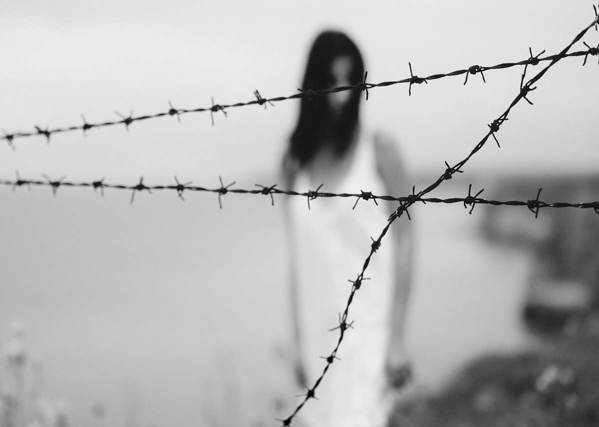 black-and-white woman standing on shore near barbed wire fence wire