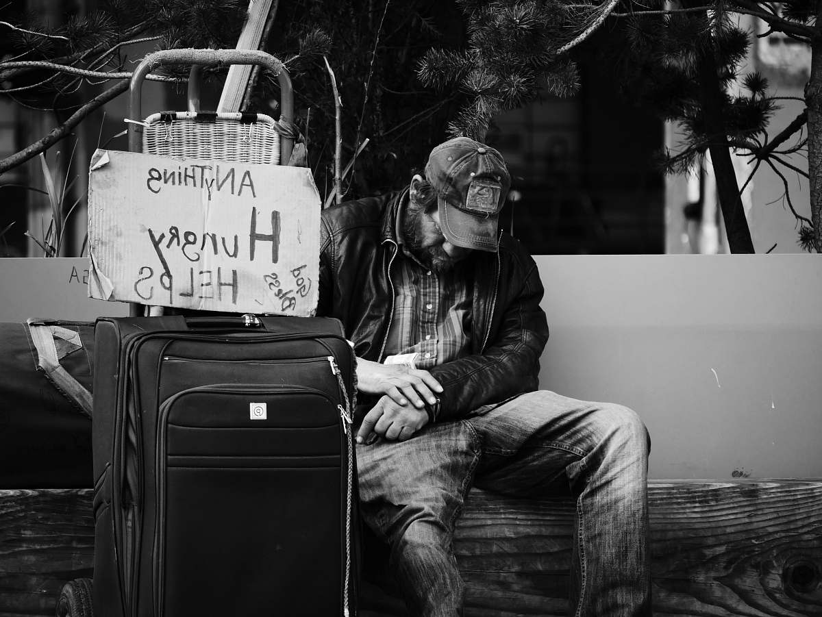 black-and-white grayscale photography of man sitting on chair suitcase