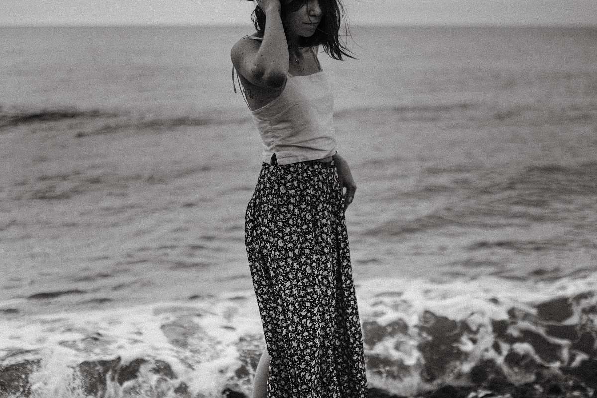 human grayscale photography of woman standing on shore black-and-white