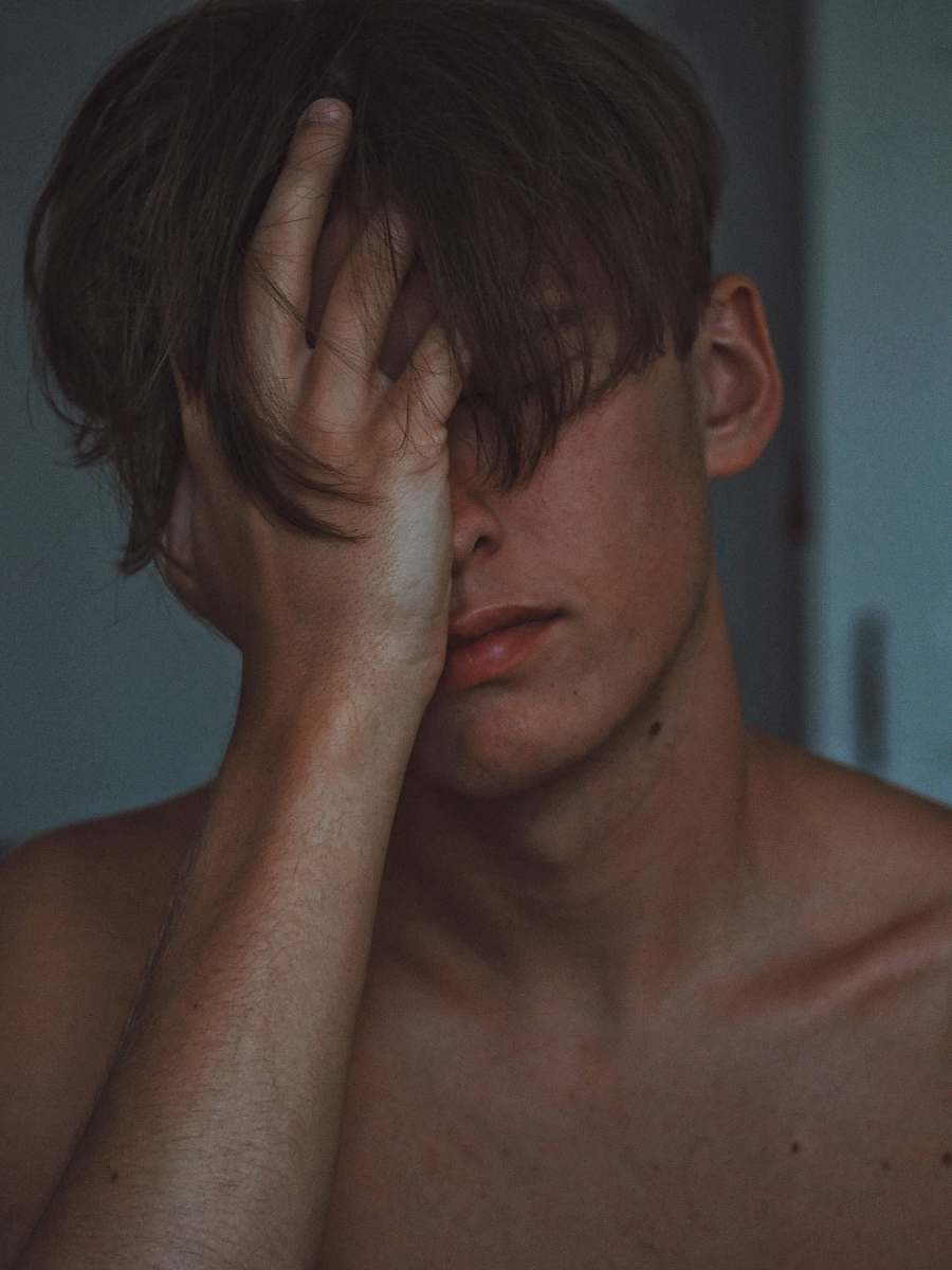 face man covering face using right hand skin