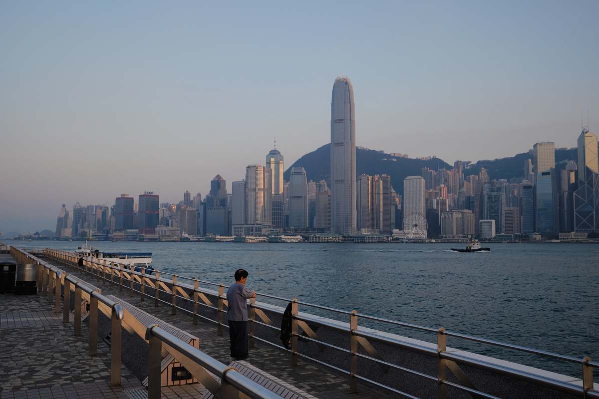 human person standing on pier near the city during day railing