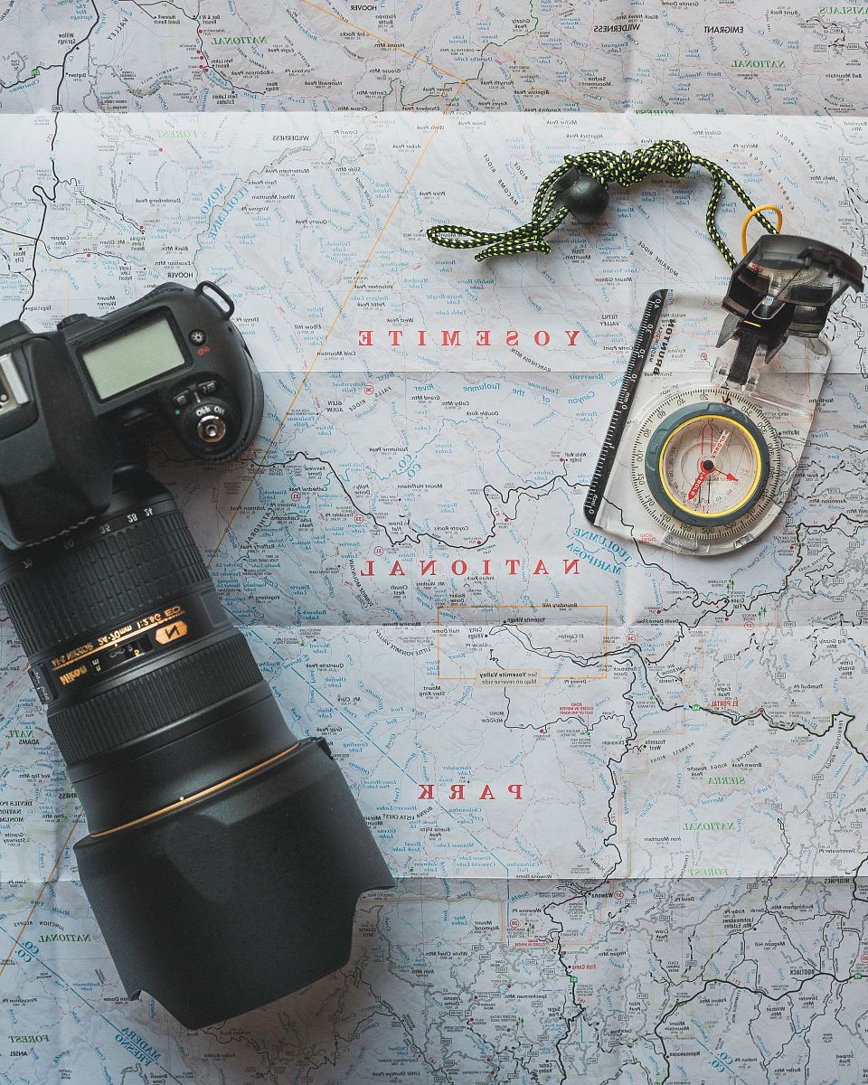 black Nikon DSLR camera beside of map compass