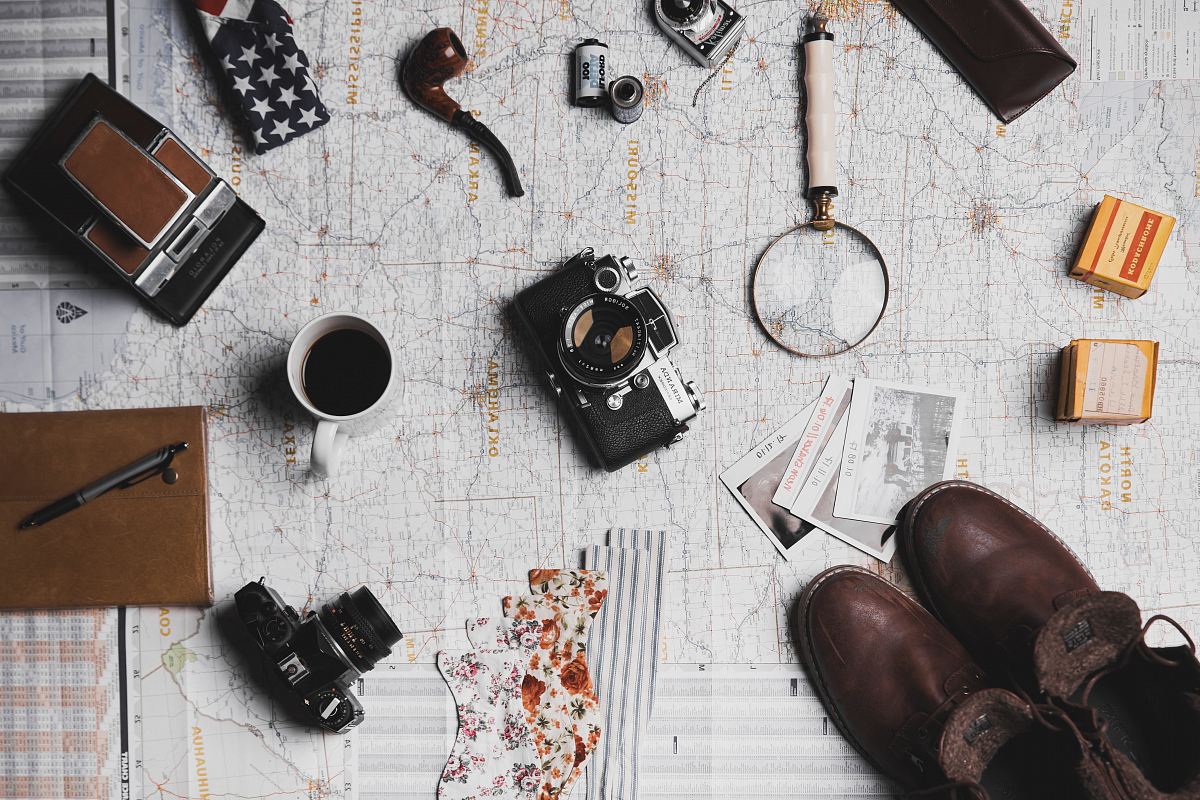 camera, pair of brown shoes, white ceramic mug, grey and black pen, brown smoking pipe