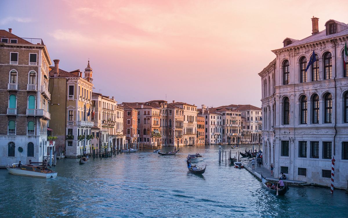 photo of gondolas on body of water between buildings
