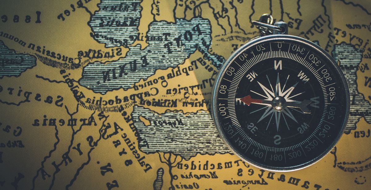 round gray framed compass on brown map