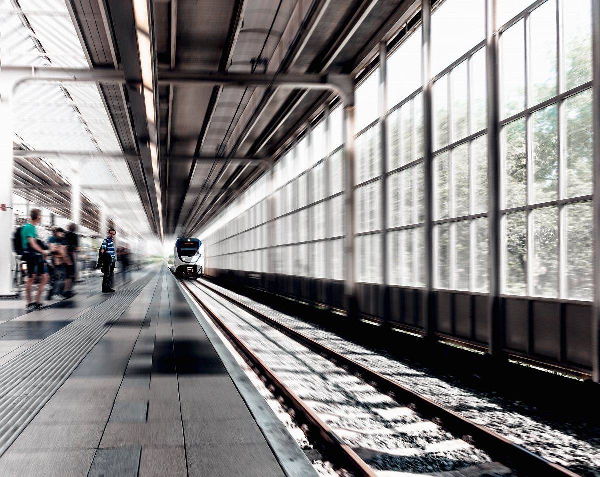 time lapse photo of train running on train station with people beside during daytime
