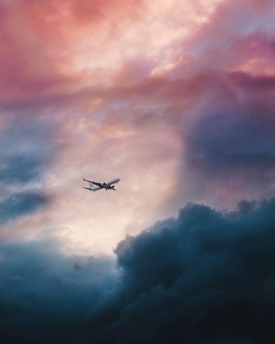 white plane flying over gray clouds