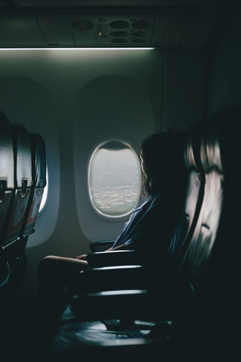 woman sits on seat near window inside plane