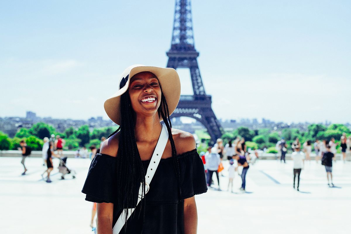 woman standing behind Eiffel Tower during daytime