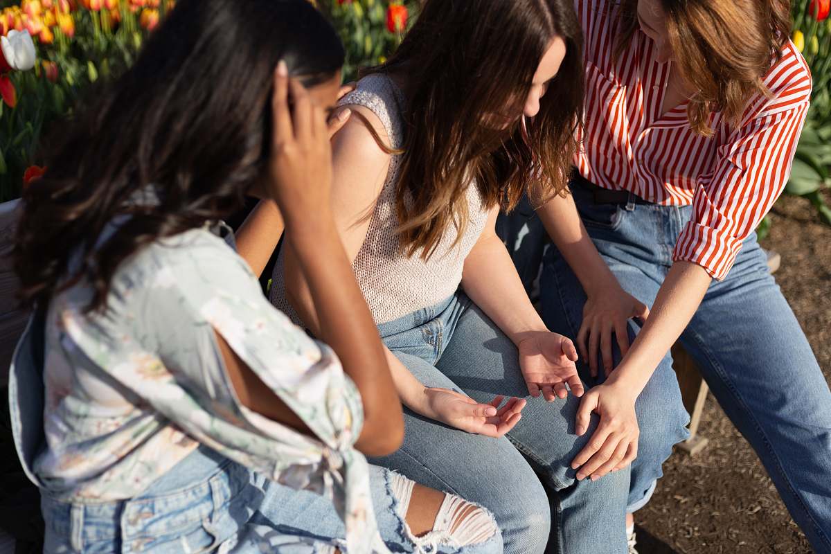 person three woman sitting at each other near flowers apparel