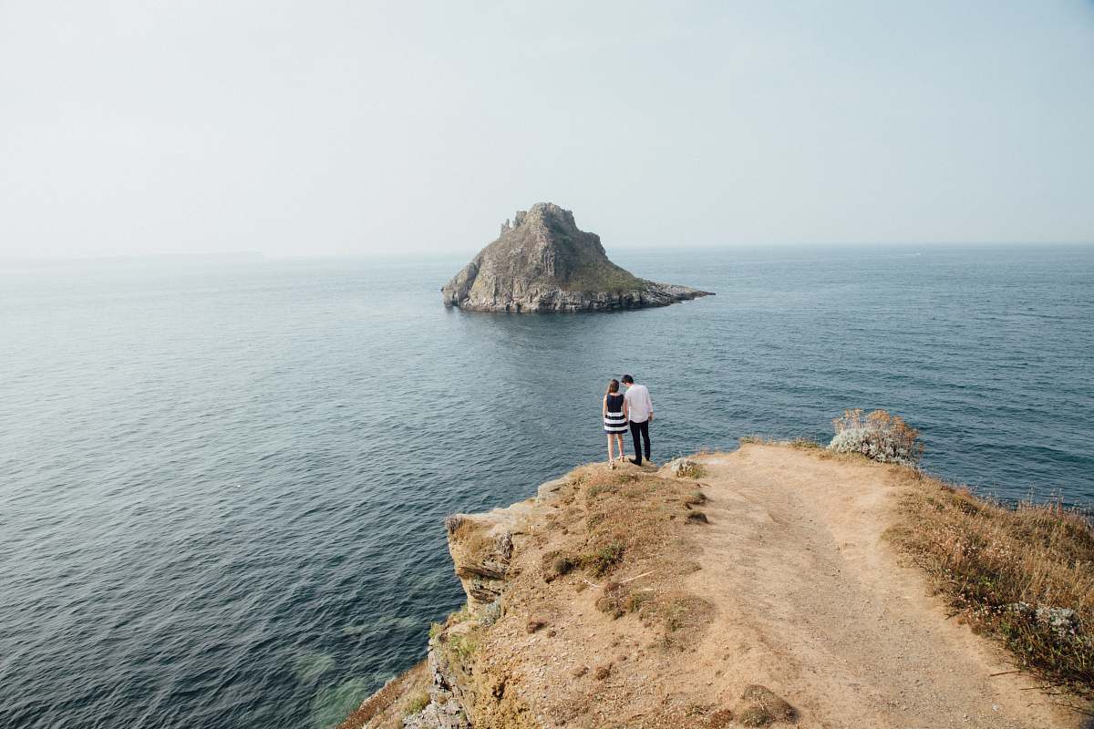sea aerial photography of man and woman near cliff water