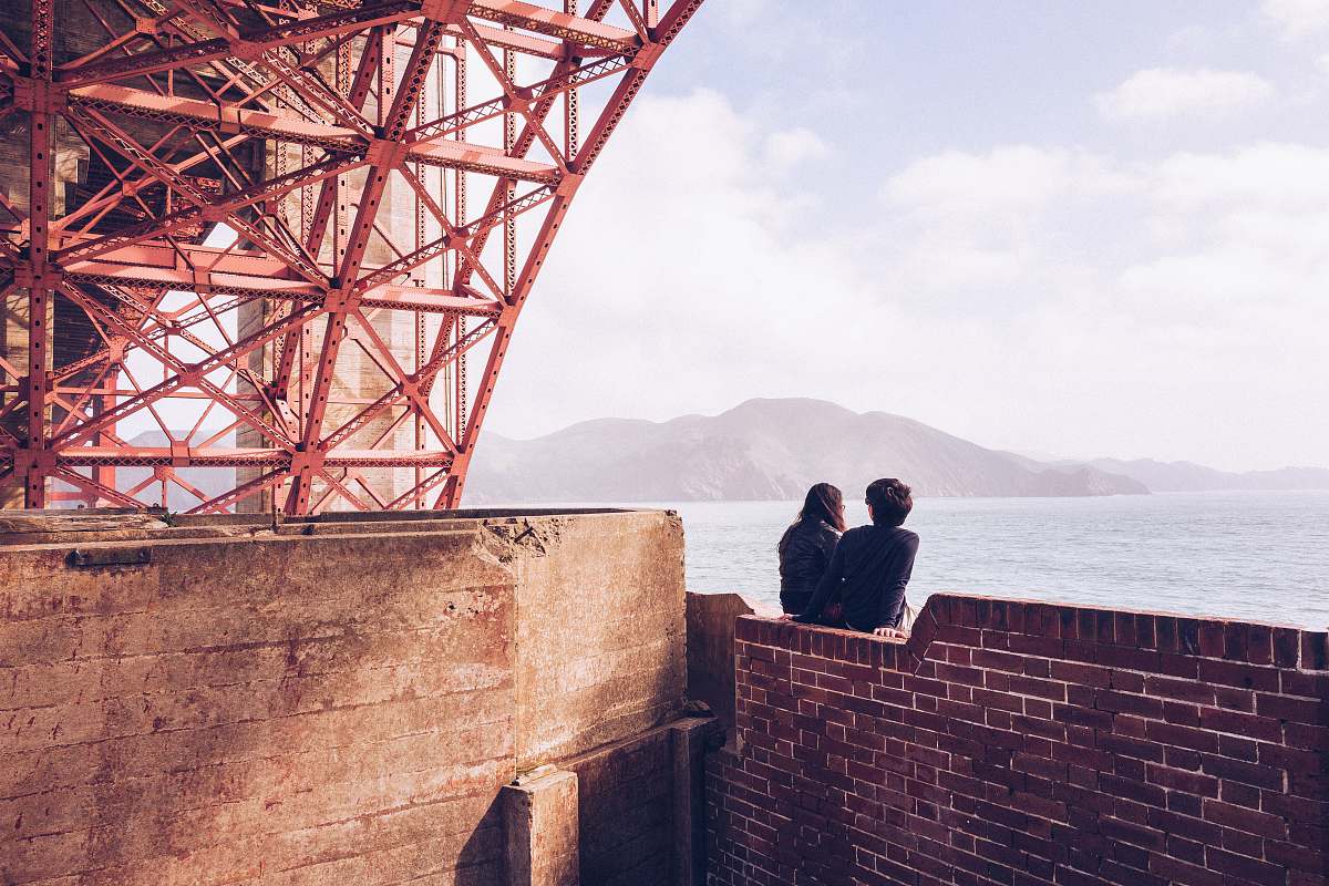 human man and woman sitting in bricked wall during daytime person