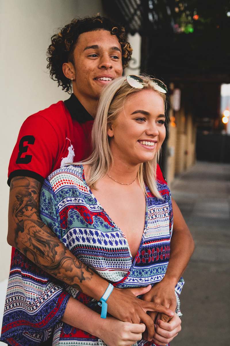 human man in red t-shirt hugging woman person