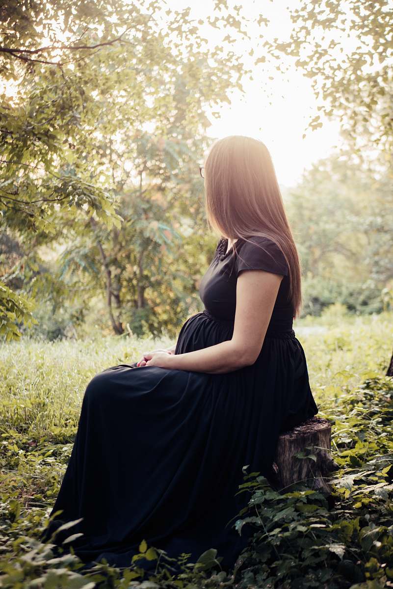 human woman sitting on tree stump surrounded by plants people